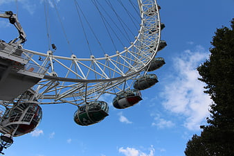 Low angle view of London Eye Ferris wheel against blue sky