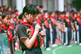 Young Girl with Red Scarf Speaking into Microphone at School Event