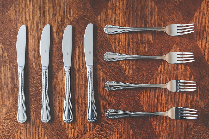 Silver knives and forks on wooden table