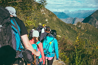 Group of hikers with backpacks walking on a mountain trail