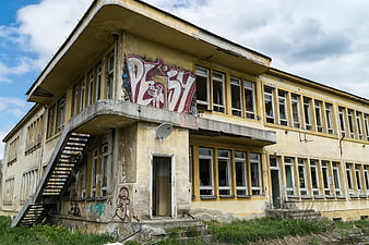 Abandoned yellow building with graffiti and broken windows