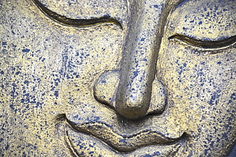 Close-up of weathered golden Buddha face statue texture