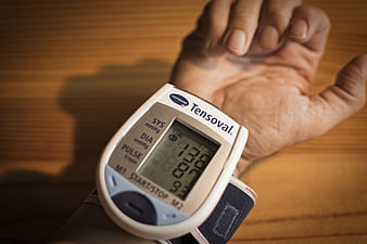 Digital Blood Pressure Monitor On Wrist With Hand In Background