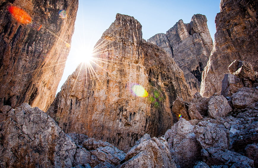 Sunburst shining through rugged mountain rock formations