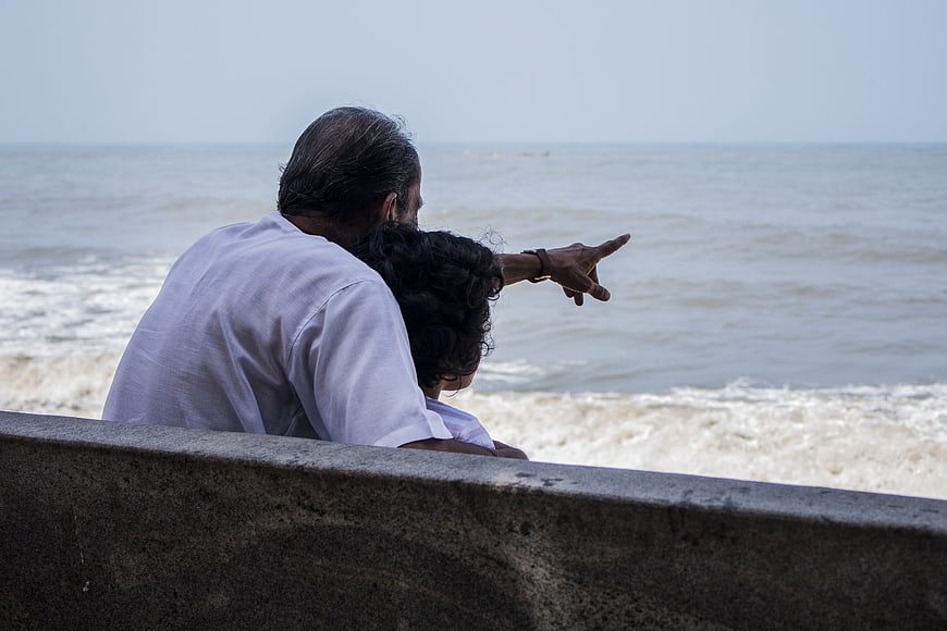 Senior Man and Child Pointing at Ocean Waves