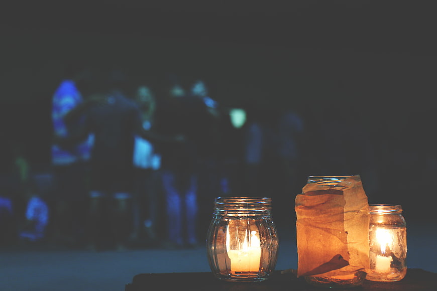 Candles in glass jars with blurred party background