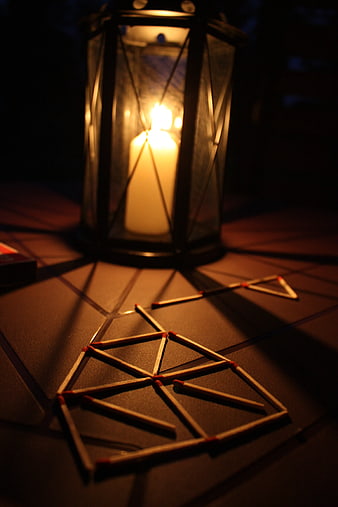 Matches arranged in geometric patterns on a table with a lantern