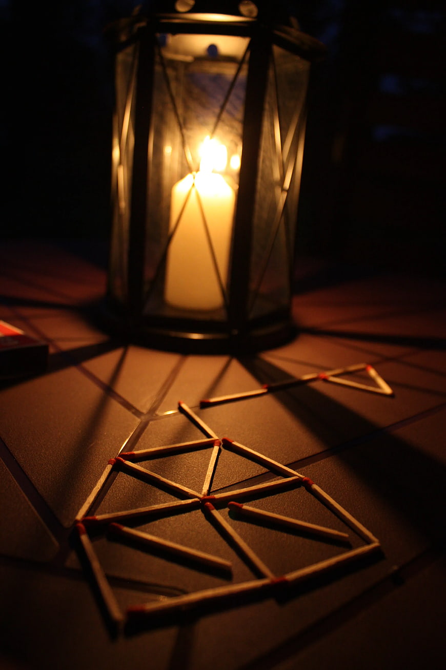 Matches arranged in geometric patterns on a table with a lantern