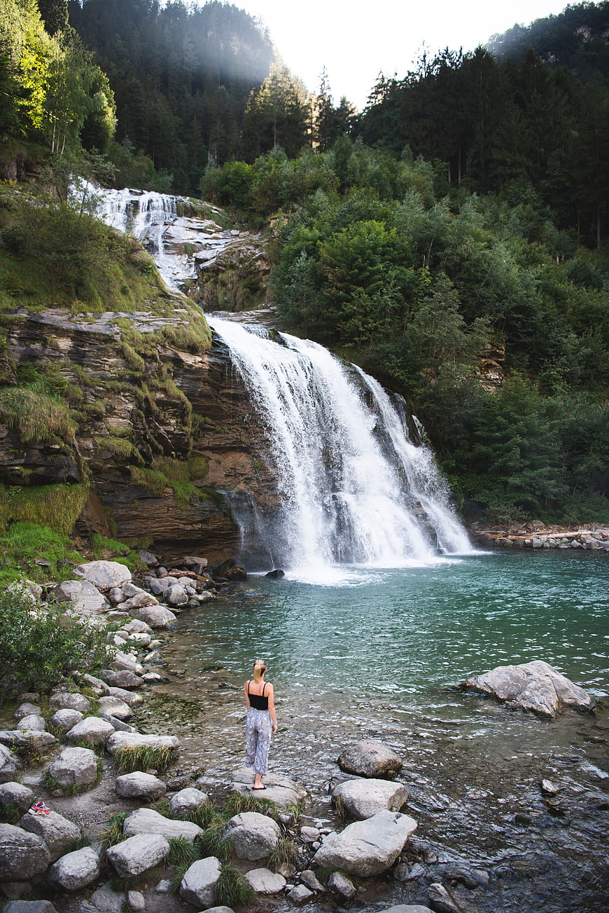 Woman standing by a cascading waterfall in a lush forest