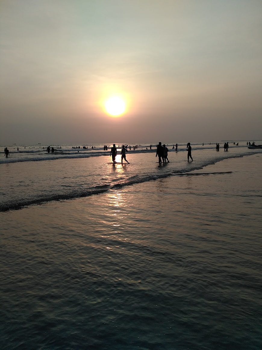 Silhouettes of People Walking on Beach at Sunset