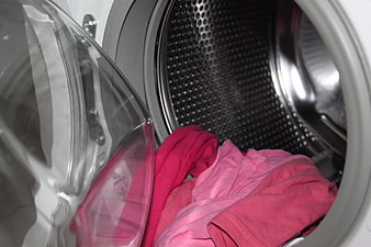 Pink clothes inside open washing machine drum