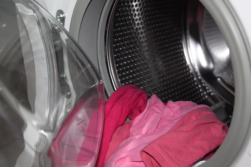 Pink clothes inside open washing machine drum
