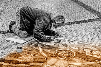 Elderly street artist creating religious chalk drawing on pavement