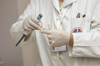 Scientist using pipette in laboratory with white coat