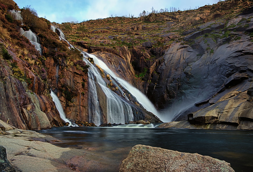 Majestic waterfall cascading down rocky cliffs into a serene pool