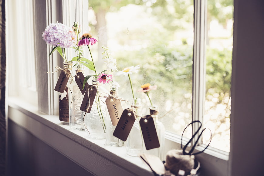 Dried wildflowers in glass bottles on a sunny windowsill