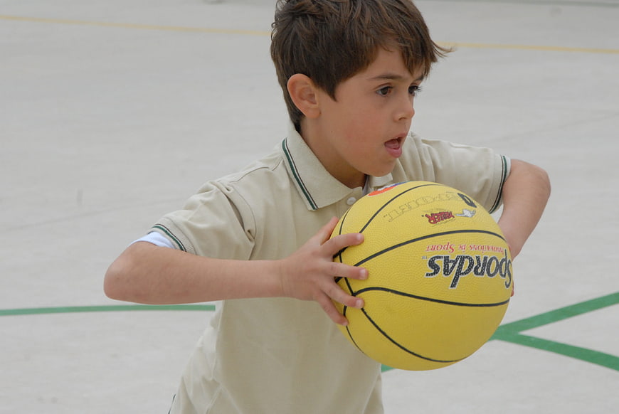 Young Boy Playing Basketball in School Gymnasium