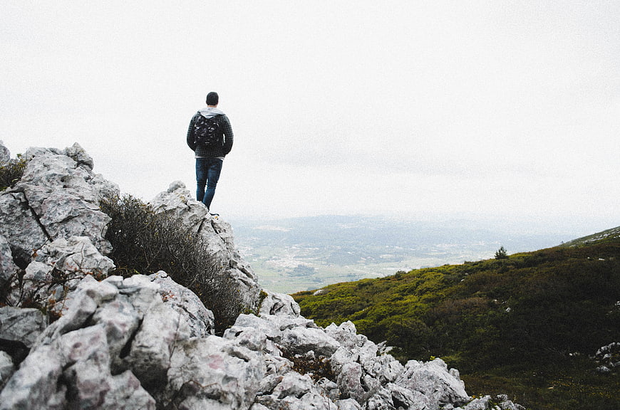 Man standing on rocky mountain peak overlooking valley