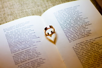 Gold wedding ring on open book with Russian poetry