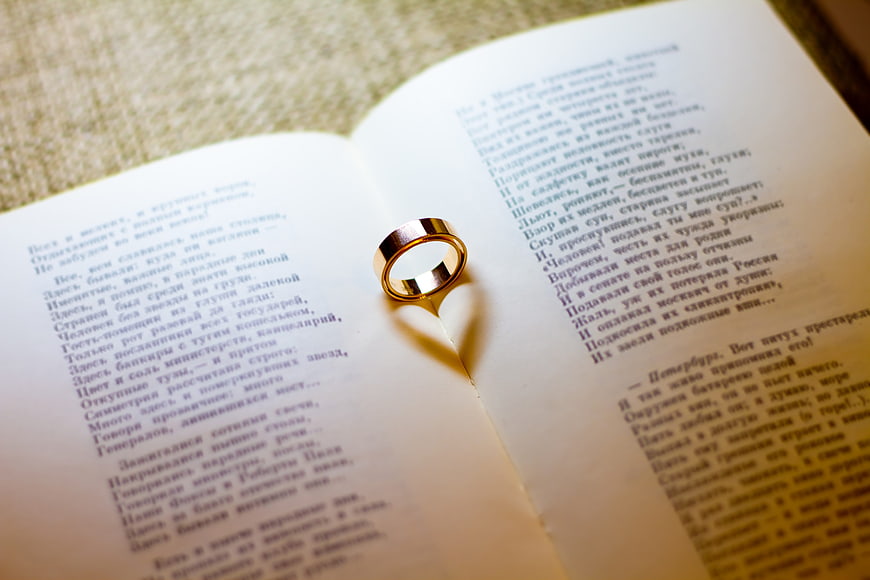Gold wedding ring on open book with Russian poetry