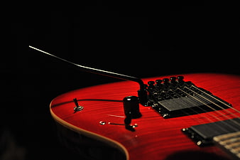 Close-up of red electric guitar body and bridge on black background