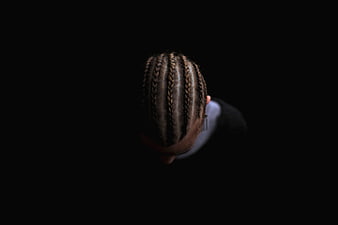 Top-down view of woman with cornrow braids on black background