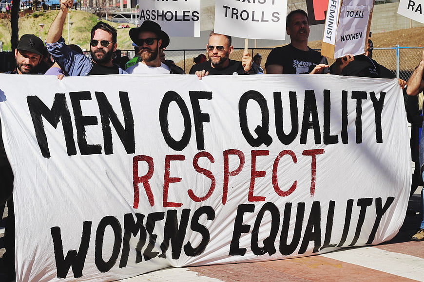 Men holding protest banner for women's equality and respect