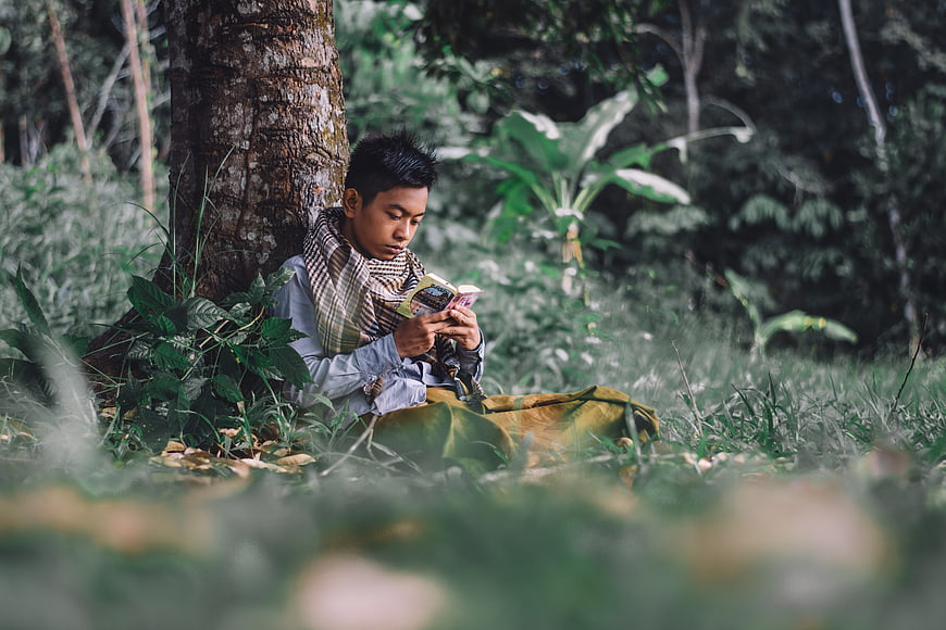 Young Muslim Man Reading Quran Under Tree In Forest
