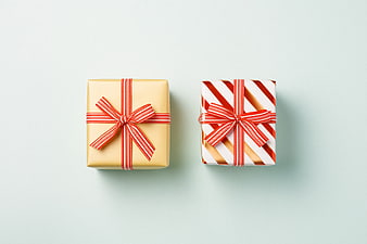 Two wrapped gift boxes with red ribbons on pastel background
