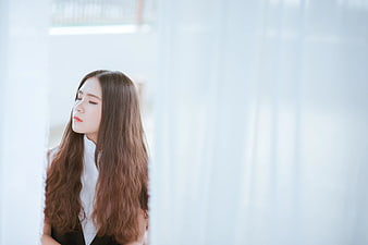 Serene woman with long brown hair in white shirt