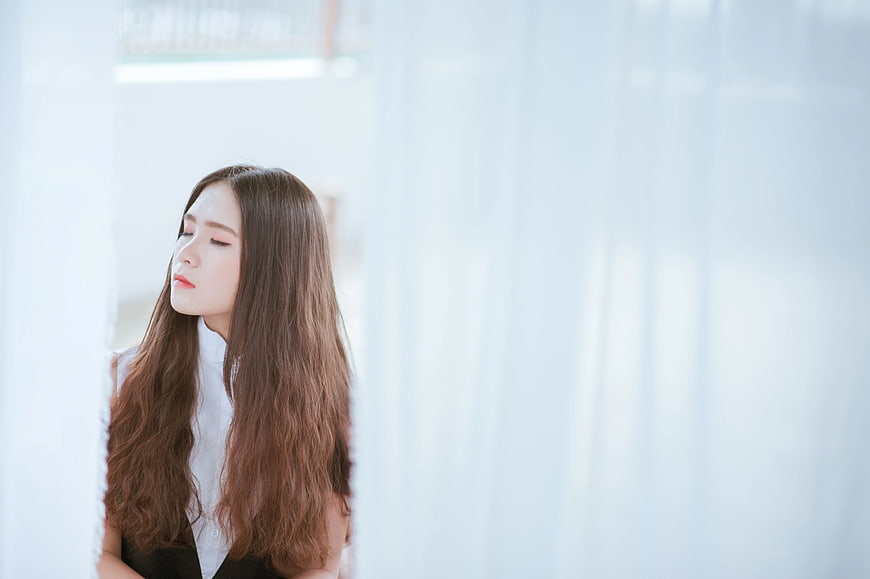 Serene woman with long brown hair in white shirt