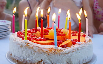 Homemade birthday cake with fruit and lit candles