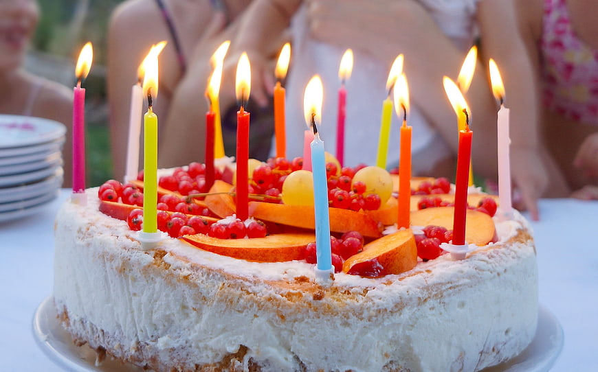 Homemade birthday cake with fruit and lit candles