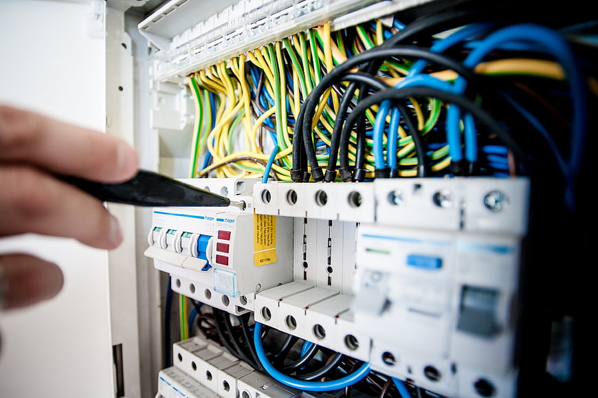 Electrician repairing circuit breaker panel with screwdriver