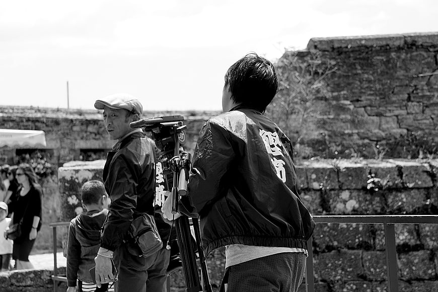 Cameraman filming at ancient stone ruins in black and white