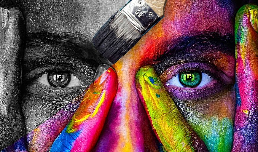 Close-up of face being painted with vibrant rainbow colors