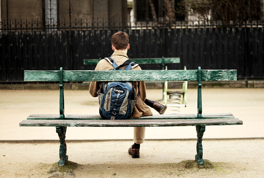 Man with Backpack Sitting Alone on Park Bench