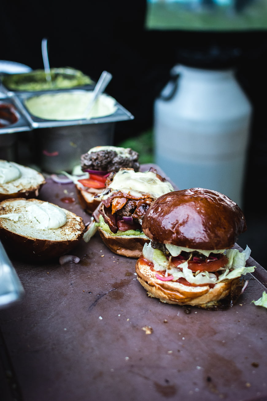 Gourmet burgers being prepared on a wooden board