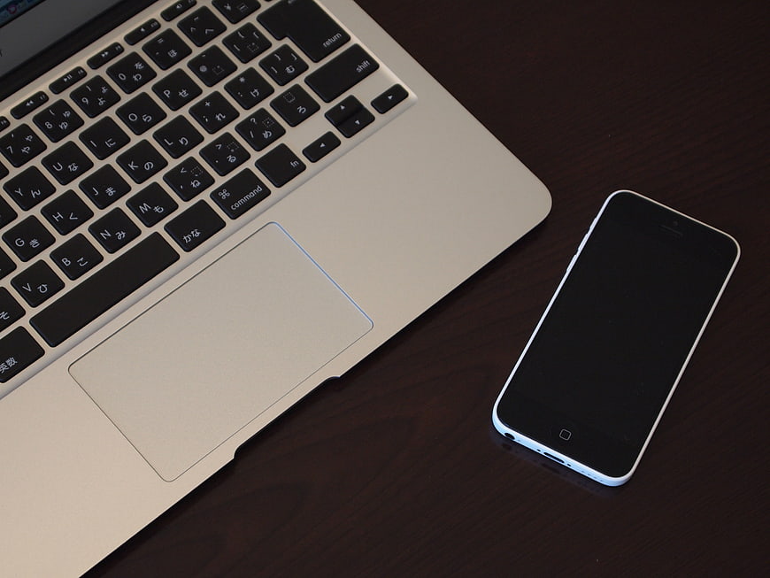 Silver MacBook Air and White iPhone 5c on Dark Wood Desk