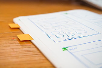 Hand-drawn wireframe sketch on notebook with sticky notes