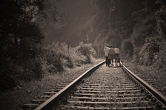 Three people walking away on railway tracks in sepia tone