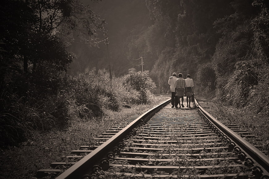 Three people walking away on railway tracks in sepia tone