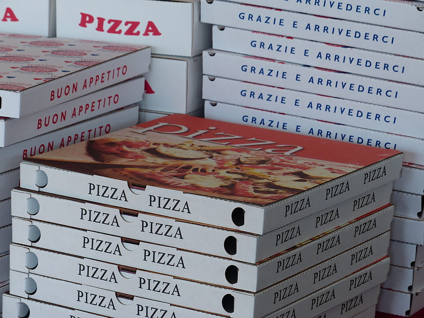 Stacks of white pizza delivery boxes with Italian text