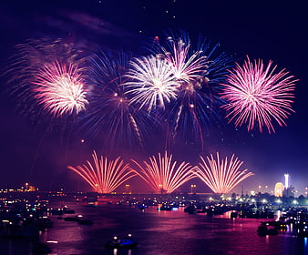 Vibrant Fireworks Display Over Waterfront City At Night