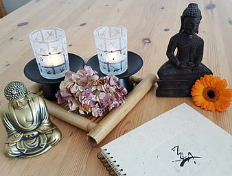 Zen meditation setup with Buddha statues, candles, and dried flowers on wood