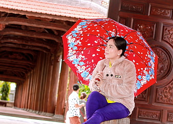 Woman with Red Floral Umbrella Sitting on Wooden Bridge