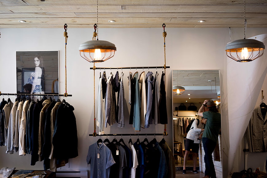 Modern Clothing Store Interior with Hanging Racks and Shoppers