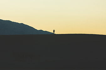 Silhouette of Man Standing on Hill Against Sunset Sky