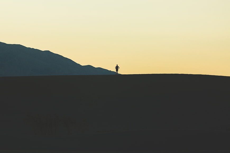 Silhouette of Man Standing on Hill Against Sunset Sky