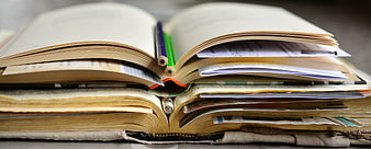 Stack of open books with pencils and papers for study
